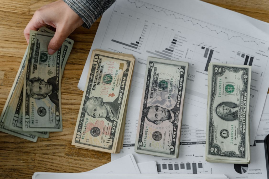 A person placing dollar bills on top of papers on a table