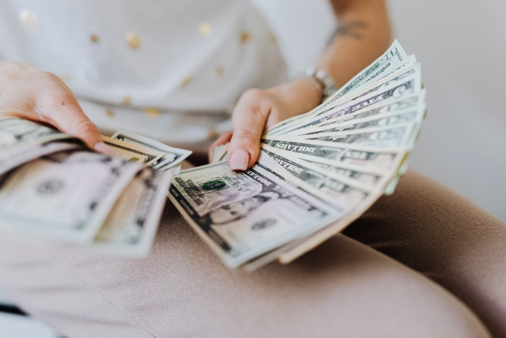 A person holding a fan of US dollar bills 